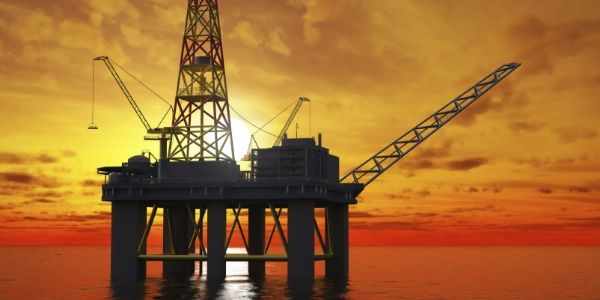 The offshore oil production equipment is working under sunset.